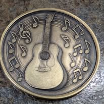 Coin engraved with an acoustic guitar surrounded by music notes