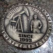 Coin engraved with an oil pumpjack and a rig worker, reading Oilfield Trash Since 1993