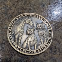 Coin engraved with a horse, dog, and cat, reading Animals Need Someone to Love