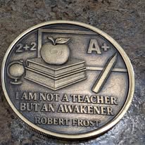 Coin engraved with an apple, book, and a Robert Frost quote about teaching