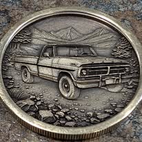 Coin engraved with a vintage pickup truck in front of mountains